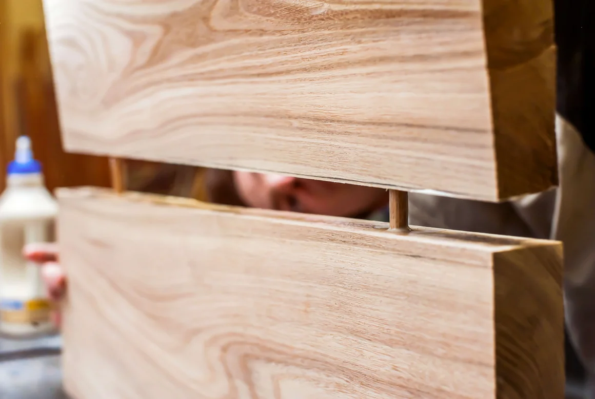 Person verbindet zwei Holzstücke mit Dübel